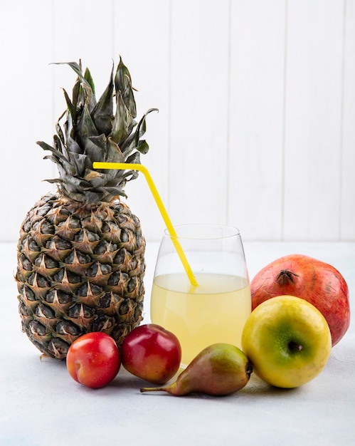 Vue avant des fruits comme ananas prune pomme pêche et grenade avec du jus d'ananas sur une surface blanche