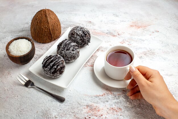 Vue avant des gâteaux au chocolat avec une tasse de thé sur le bureau blanc gâteau au chocolat biscuit sucre biscuits sucrés