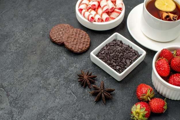 Vue avant des goûts délicieux avec une tasse de tranches de thé de biscuits au citron et de fruits frais