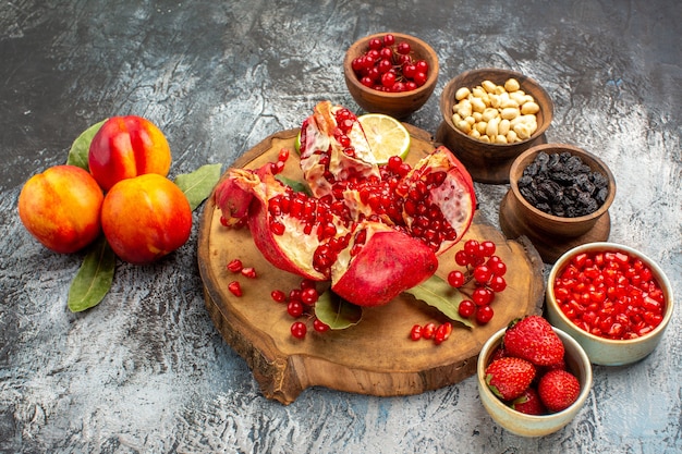 Vue avant des grenades en tranches avec d'autres fruits sur les fruits d'arbre de table clair-foncé