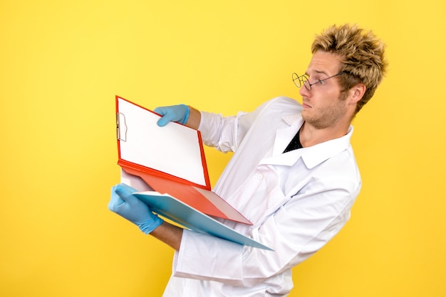 Photo gratuite vue avant de l'homme médecin avec analyses sur fond jaune santé medic covid humain