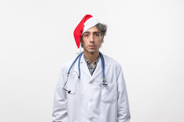Vue avant de l'homme médecin en bonnet rouge sur le mur blanc de l'hôpital de vacances du nouvel an