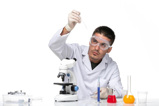 Vue avant de l'homme médecin en costume médical blanc avec des gants et des lunettes de soleil de protection sur l'espace blanc