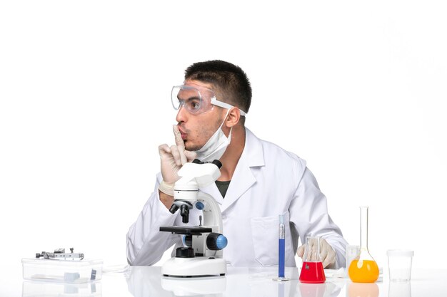 Vue avant de l'homme médecin en costume médical blanc avec masque en raison de covid sur l'espace blanc