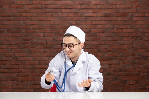 Vue avant de l'homme médecin en costume médical blanc avec stéthoscope