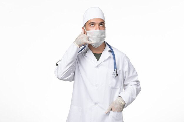 Vue avant de l'homme médecin en costume médical et portant un masque contre covid sur light desk virus pandémique de la maladie de covid médecine