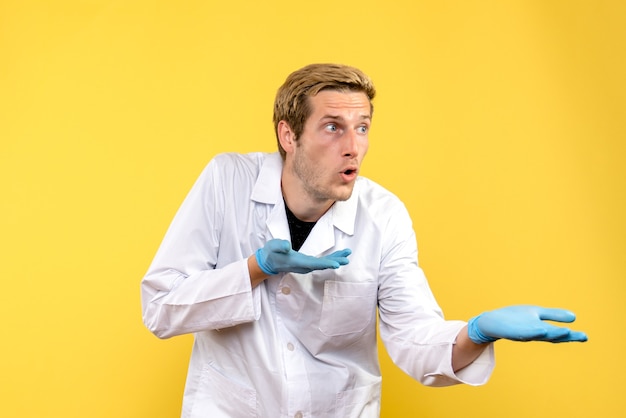 Vue avant de l'homme médecin sur fond jaune infirmier de l'hôpital covid humain