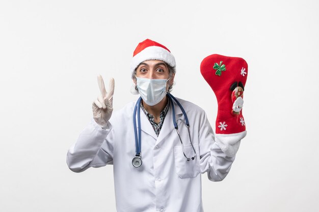 Vue avant de l'homme médecin avec grosse chaussette rouge sur mur blanc virus covid- noël