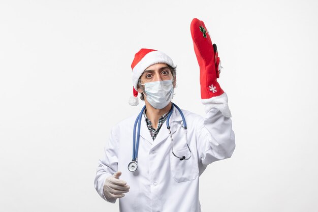 Vue avant de l'homme médecin avec grosse chaussette rouge sur le virus du mur blanc covid- vacances de Noël
