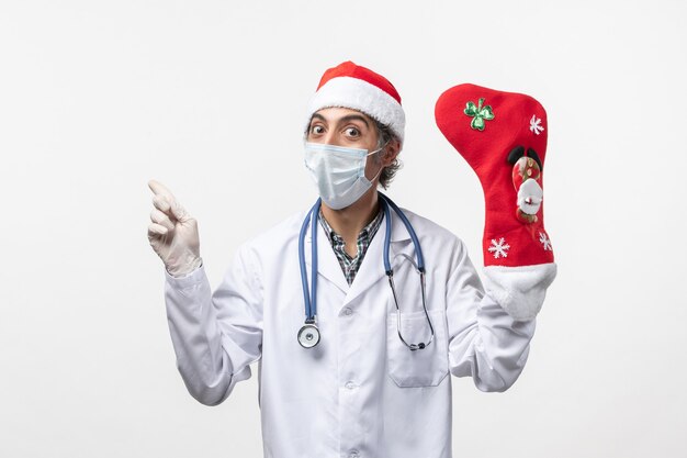 Vue avant de l'homme médecin avec grosse chaussette de vacances sur mur blanc virus de Noël covid