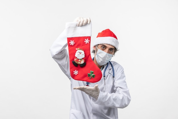 Vue avant de l'homme médecin avec grosse chaussette de vacances sur mur blanc virus de Noël covid