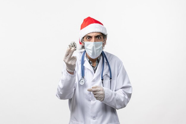 Vue avant de l'homme médecin avec jouet arbre de nouvel an sur le bureau blanc virus santé covid-