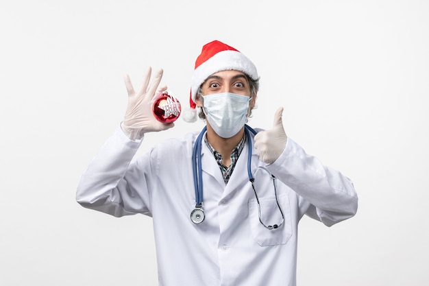 Vue avant de l'homme médecin en masque avec jouet sur mur blanc virus de la santé nouvelle année covid