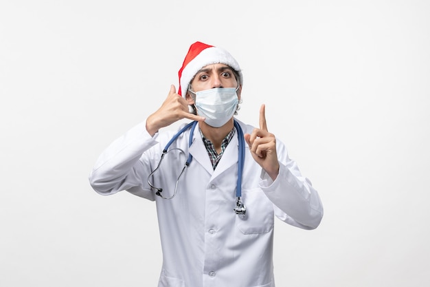 Vue avant de l'homme médecin avec masque sur un mur blanc virus pandémique covid vacances
