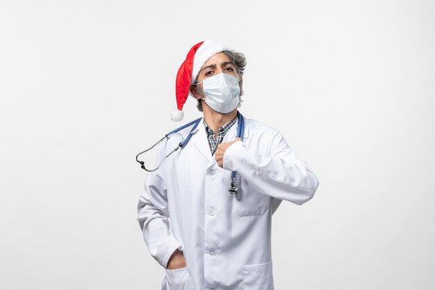 Vue avant de l'homme médecin en masque stérile sur mur blanc pandémie de nouvel an virus covid