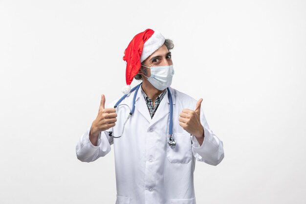 Vue avant de l'homme médecin en masque stérile sur mur blanc vacances de nouvel an virus covid