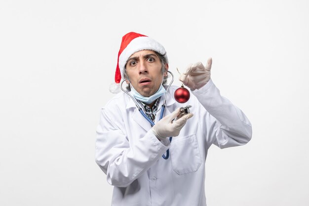 Vue avant de l'homme médecin observant jouet sur mur blanc virus covid santé nouvelle année
