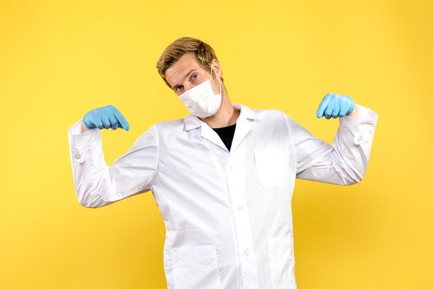 Vue avant de l'homme médecin pointant sur fond jaune pandémie covid santé medic