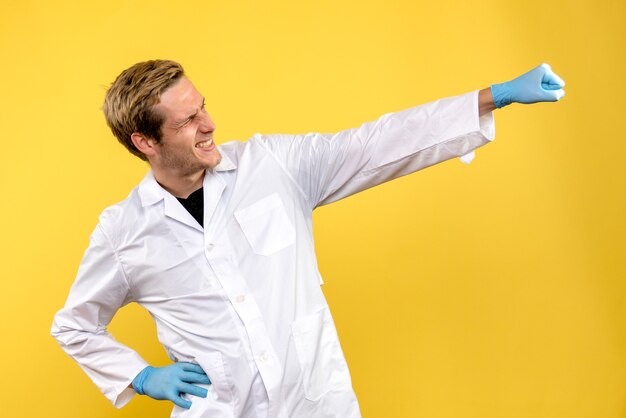 Vue avant de l'homme médecin se réjouissant sur fond jaune covid- médecin de l'hôpital humain