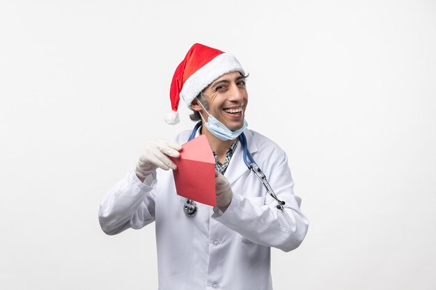 Vue avant de l'homme médecin tenant une enveloppe rouge sur le virus de bureau blanc covid- santé