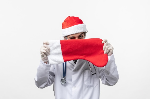 Vue avant de l'homme médecin tenant de grandes chaussettes de vacances sur le virus mur blanc nouvel an vacances covid