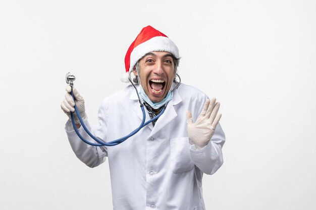 Vue avant de l'homme médecin tenant stéthoscope excité sur le mur blanc émotion de virus covid