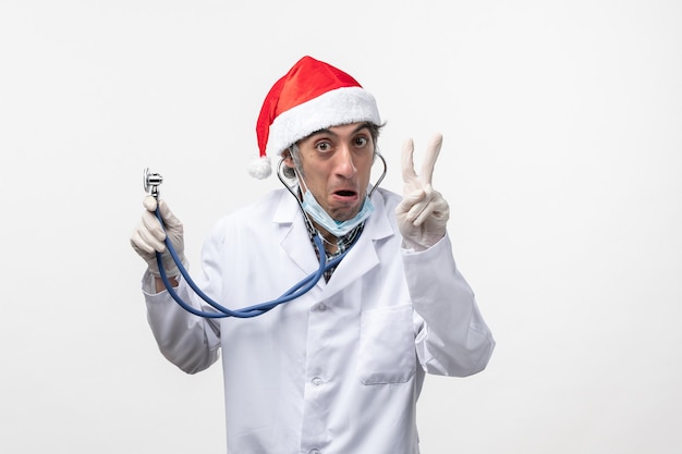 Vue avant de l'homme médecin tenant stéthoscope sur mur blanc émotion covid- virus