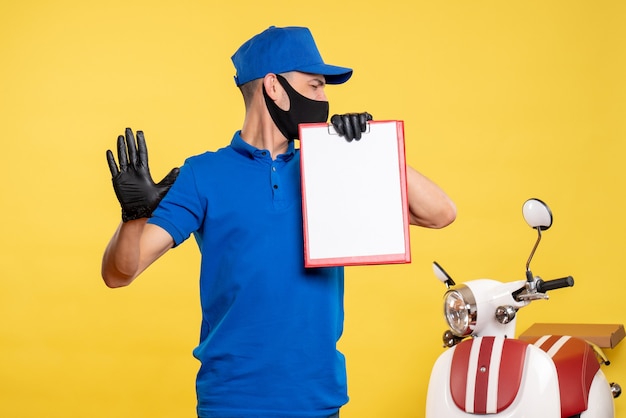 Photo gratuite vue avant de l'homme de messagerie en uniforme bleu holding note de fichier sur un service d'emploi jaune covid- livraison de travail uniforme de couleur pandémique