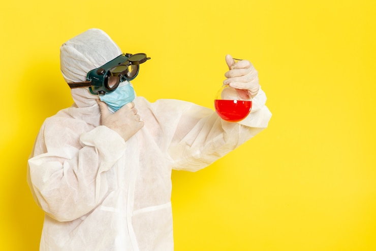 Photo gratuit vue avant de l'homme travailleur scientifique en tenue de protection spéciale tenant le flacon avec une solution rouge pensant sur la surface jaune