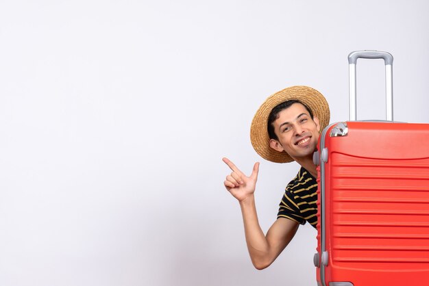 Vue avant, jeune homme, à, chapeau paille, debout, derrière, valise rouge, pointage, quelque chose