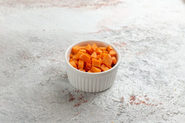 Vue avant de légume orange tranché à l'intérieur de petit pot sur une surface blanche