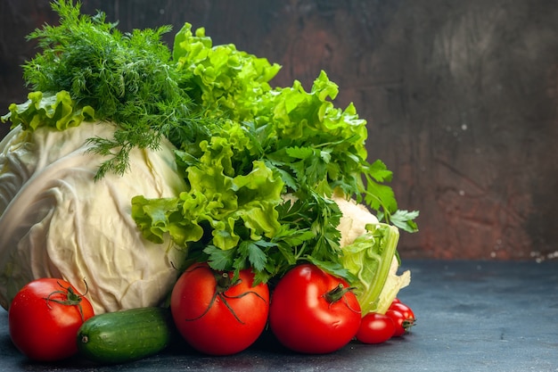 Vue avant de légumes frais chou persil poivrons laitue aneth chou-fleur tomates concombre sur surface sombre