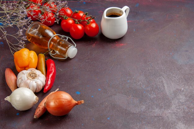 Vue avant des légumes frais avec de l'huile d'olive sur un bureau sombre