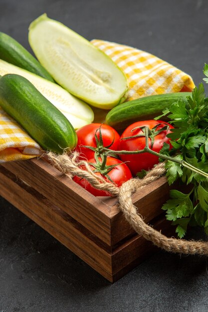 Vue avant de légumes frais tomates rouges concombres et courges avec des verts sur l'espace gris