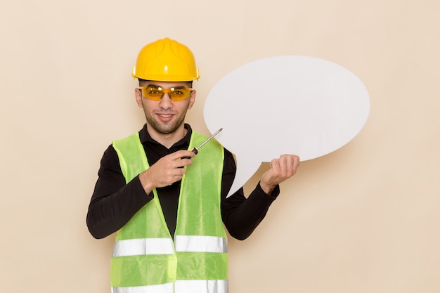 Vue avant mâle constructeur en casque jaune tenant grand panneau blanc sur le fond clair