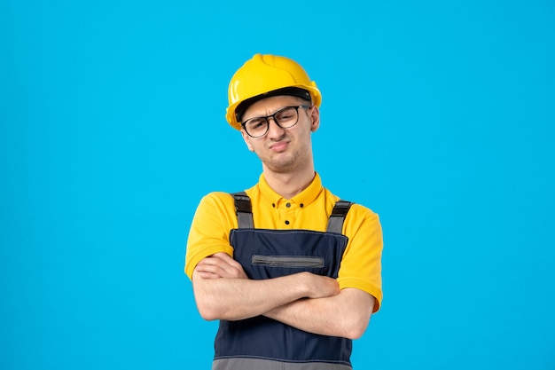 Vue avant mécontent travailleur masculin en uniforme jaune sur bleu