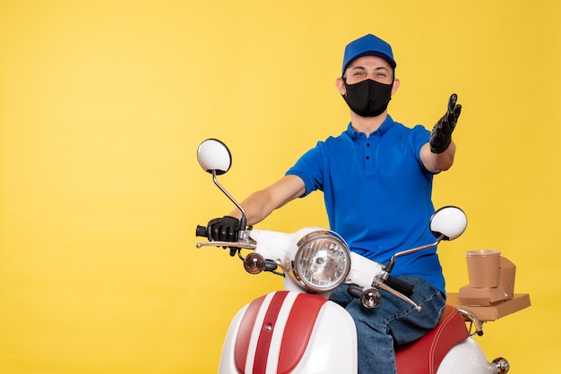 Vue avant messager masculin en uniforme bleu et masque sur un travail jaune travail de service de vélo pandémique de livraison de covid virus virus de travail