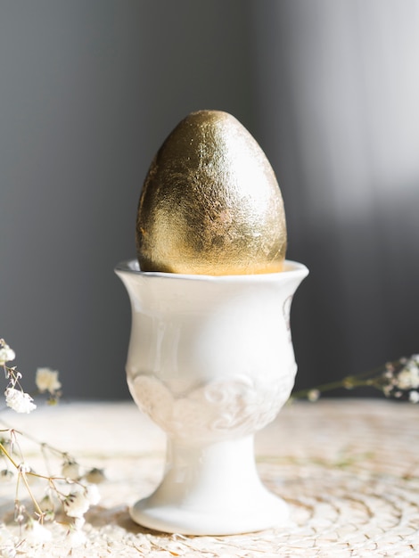 Photo gratuite vue avant de l'oeuf de pâques doré sur support avec gypsophile