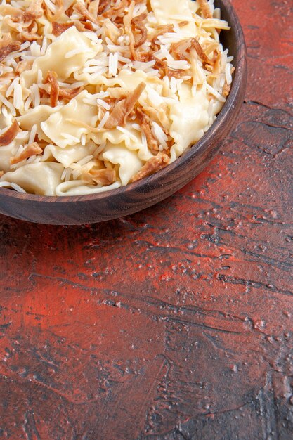 Vue avant de la pâte cuite en tranches avec du riz sur le plat de pâtes de surface sombre repas de pâte