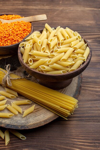 Vue avant des pâtes crues aux lentilles orange sur une surface brune