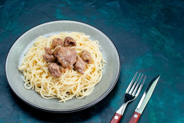 Photo gratuite vue avant des pâtes italiennes cuites avec de la viande tranchée à l'intérieur de la plaque sur la surface bleue pâtes italie nourriture dîner pâte viande