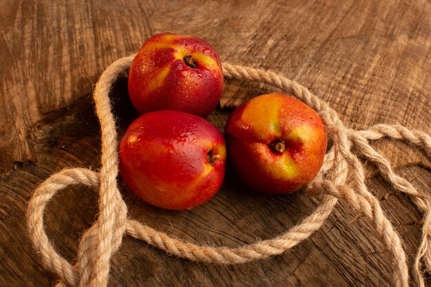 Vue avant des pêches fraîches avec des cordes sur un bureau en bois couleur fruits d'été