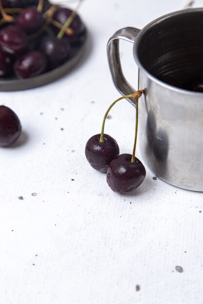 Vue avant de la plaque avec des cerises sombres aigre-douce et moelleux sur gris