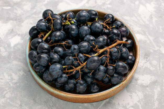 Vue avant des raisins noirs frais juteux fruits sucrés moelleux sur le bureau blanc léger fruits frais jus de fruits moelleux