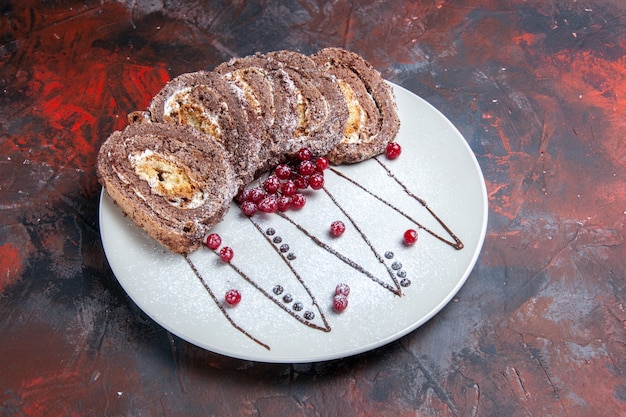 Photo gratuite vue avant des rouleaux de biscuits sucrés avec des baies à l'intérieur de la plaque sur la table sombre