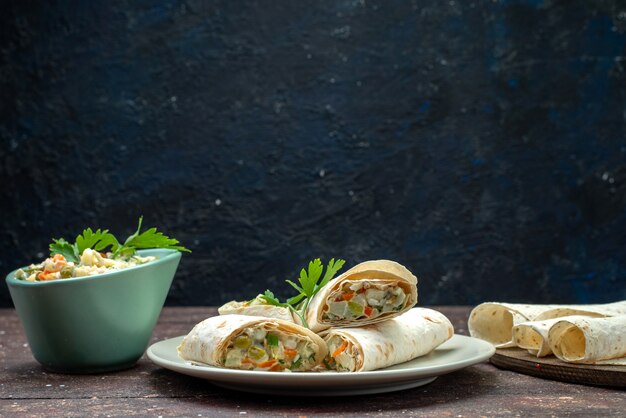 Vue avant des rouleaux de sandwich lavash en tranches avec de la salade et de la viande à l'intérieur avec salade sur brown