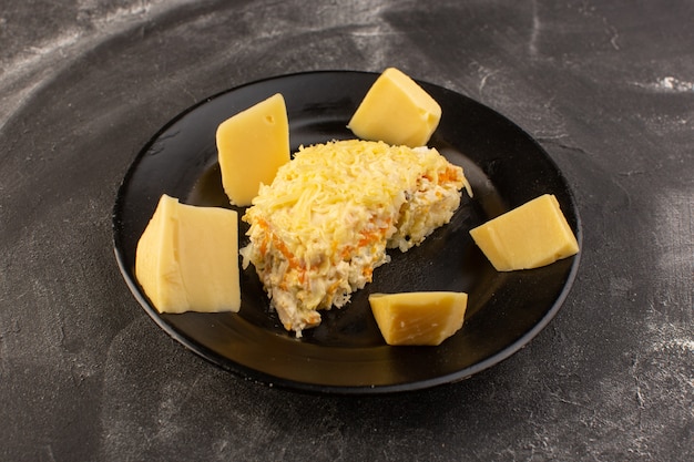 Une vue avant salade de légumes mayyonaised avec du fromage frais à l'intérieur de la plaque noire sur la table grise salade repas