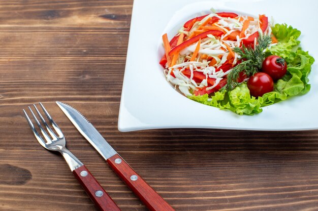 Vue avant salade de légumes avec salade verte et chou à l'intérieur de la plaque sur la surface brune