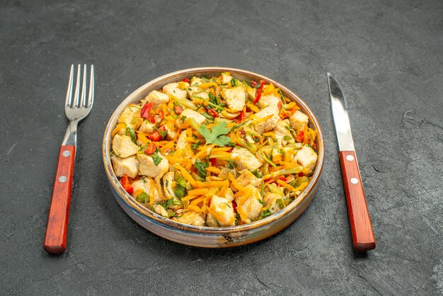 Vue avant de la salade de poulet savoureuse avec des légumes en tranches sur la santé de l'alimentation de la table sombre