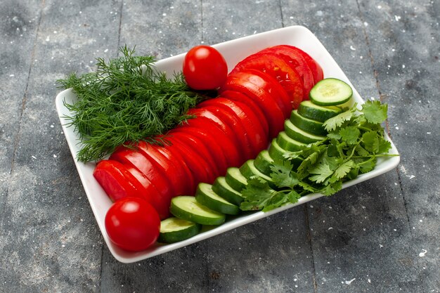 Vue avant de la salade de tomates fraîches en tranches élégamment conçu sur l'espace gris